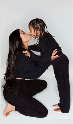 two women are sitting on the ground kissing each other and one is wearing black sweatpants