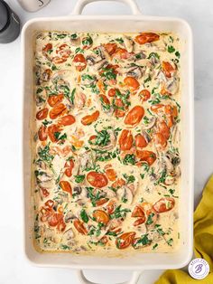 a casserole dish with tomatoes, spinach and cheese in it on a white surface