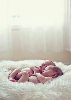 a baby laying on top of a fluffy white blanket in front of a large window