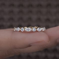 a woman's hand holding a gold ring with five diamonds on top and bottom