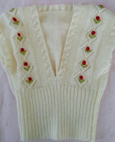 a white sweater with red flowers on the front and back, sitting on a table