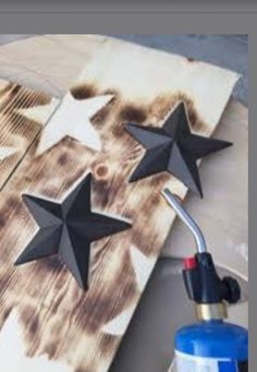 three black stars are placed on top of a piece of wood, next to a blue sprayer