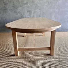 a wooden table sitting on top of a carpeted floor next to a gray wall