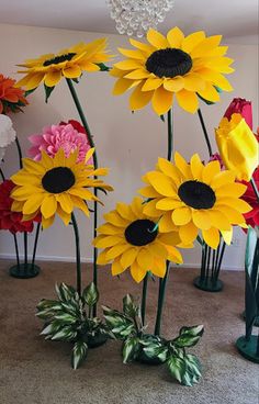 a bunch of fake sunflowers sitting on the floor in front of a chandelier