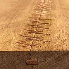 a close up of a wooden table with metal wires on the edge and wood grain