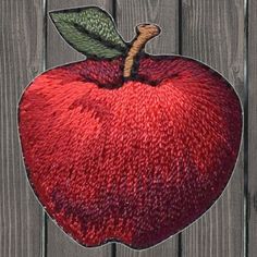 an embroidered apple sitting on top of a wooden fence