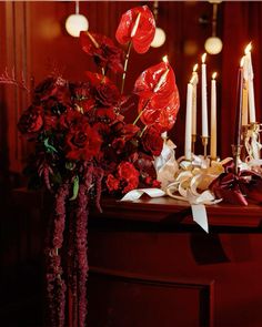 red flowers and candles are sitting on a table