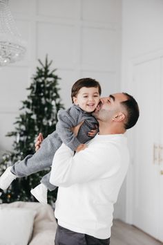 a father holding his son in front of a christmas tree