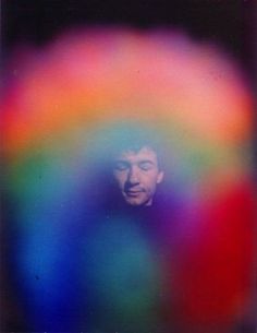 a man standing in front of a multicolored background with his face obscured by the image