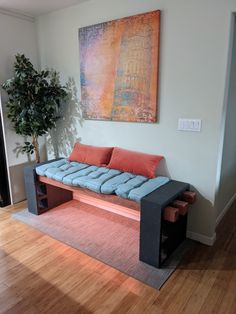 a couch sitting on top of a wooden floor next to a plant in a living room