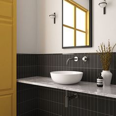 a bathroom sink sitting under a mirror next to a vase with flowers on top of it