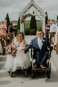 a bride and groom in a wheelchair being pulled down the aisle