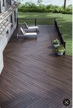 a deck with two chairs and a potted plant on the ground next to it