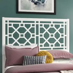 a bedroom with green walls and a white headboard that has decorative designs on it