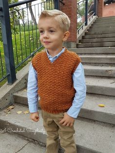 a little boy standing on some steps wearing a brown sweater vest and khaki pants