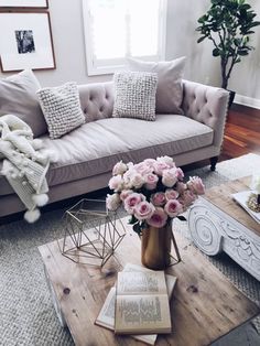 a living room filled with furniture and flowers on top of a coffee table in front of a window