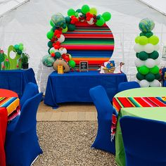 there are many balloons and decorations on the tables in this tented area for an event