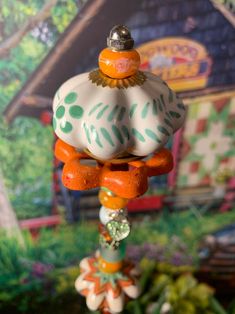 an orange, white and green wind chime hanging from a tree