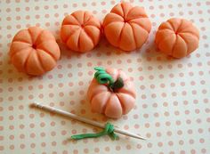 there are four small pumpkins on the table next to a pair of knitting needles