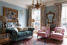 a living room filled with furniture and a chandelier hanging from the ceiling next to a window