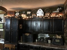 a kitchen with black cabinets and christmas lights on the top of it's cupboards