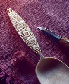 a knife sitting on top of a table next to a spoon