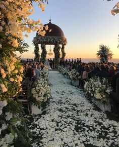 an outdoor ceremony with white flowers and greenery on the aisle, overlooking the ocean