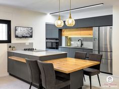 a modern kitchen with an island table surrounded by gray chairs and pendant lights hanging from the ceiling