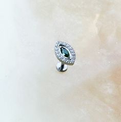 an image of a ring with diamonds on it and a green stone in the middle