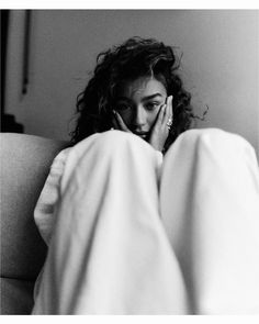 a black and white photo of a woman laying in bed with her hands on her face