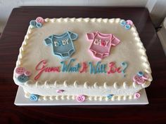 a baby shower cake is decorated with pink, blue and white icing on a wooden table