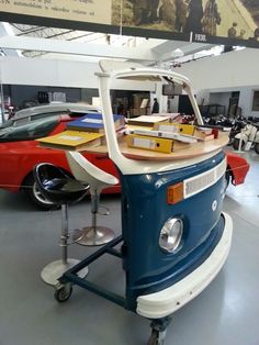 an old blue and white car is on display in a museum with other cars behind it