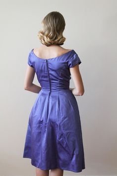 "Vintage 1960's Violet / Blue Satin Party Dress with Asymmetrical pleats. Fit & Flare style with a short cap sleeve Dress has heavy interfacing and a horsehair hem, giving a thick sturdy feel. The dress does have some water damage on the front, though it is not noticeable until close inspection. Measurements Shoulders: 16.5\" / Sleeves: 35\" / Bust: 32'' / Waist: 24.5'' / Hip: free / Length Shoulder to Hem: 42'' Model Measurements: Bust: 33\" / Waist: 24.5\" / Hip: 37\" / Height: 5'6\" - 5'7 Purple Sleeveless Satin Party Dress, Purple Satin Dress Short Sleeve, Sleeveless Purple Satin Party Dress, Purple Sleeveless Silk Satin Dress, Satin Party Dress, 1960s Purple Dress, Horsehair Hem, Cap Sleeve Dress, Most Beautiful Dresses