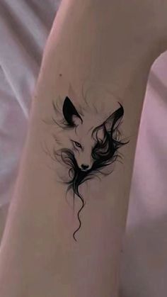 a woman's arm with a tattoo on it that has an image of a wolf