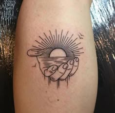 a tattoo on the leg of a person holding a sun in their hand with rays coming out