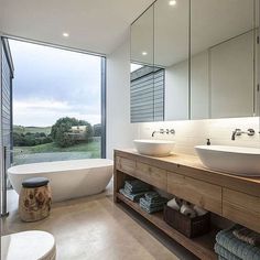 a bathroom with two sinks and a bathtub in front of a large glass window