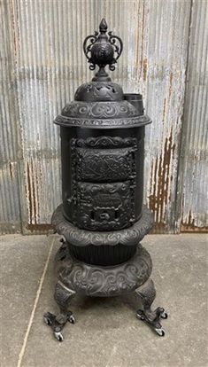 an old fashioned cast iron stove sitting on top of a cement floor next to a wall