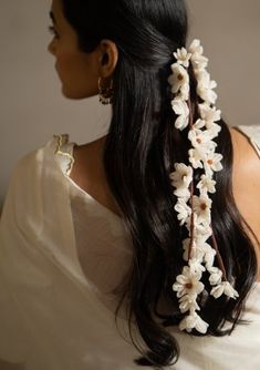 a woman with long black hair wearing a white dress and flowered headpieces