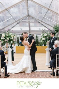 a bride and groom kissing under a clear tent