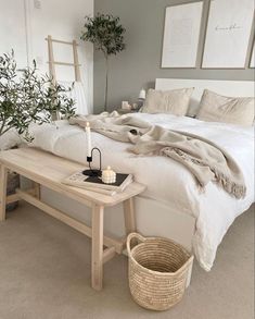 a bed with white linens and pillows in a bedroom next to a basket on the floor