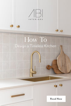 a white kitchen with gold faucet and wooden cutting board on the counter top