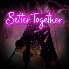 a couple standing under a neon sign that says better together