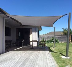 an outdoor patio with wooden decking and large gray awning over the dining area