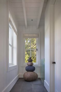 three rocks stacked on top of each other in front of a window with white trim