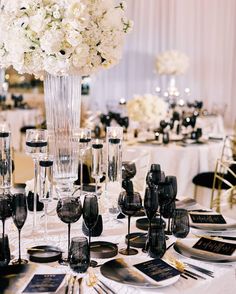 the table is set with black and white place settings, silverware, and flowers