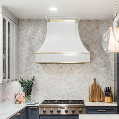 a kitchen with blue cabinets and white counter tops, an oven hood over the stove