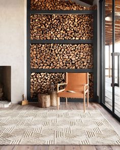 a living room with wood stacked on the wall and a chair in front of it