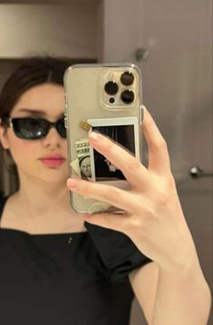 a woman taking a selfie in the mirror with her cell phone and sunglasses on