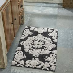 a black and white rug sitting on top of a floor next to a wooden cabinet