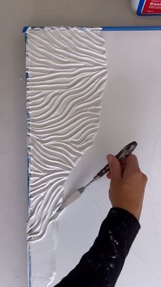 a person is using a paintbrush to decorate a piece of art on the wall